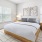 spacious bedroom with large window, side tables and wall decor